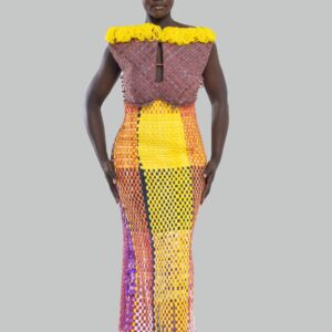 Plus qu’un vêtement, cette robe est une œuvre d’art, un dialogue entre force et couleur, entre tradition et modernité. Conçue pour la femme Kroskel qui avance avec assurance, elle incarne la puissance de celles qui tissent ensemble un avenir lumineux. Le buste, minutieusement travaillé, est inspiré des cases africaines et de leurs toits de paille. Les nœuds délicatement tissés viennent se poser comme des symboles de protection et d’ancrage, tandis que la couleur jaune éclatante illumine l’ensemble, porteuse d’espoir et de renouveau. Sa coupe majestueuse met en valeur la silhouette avec une jupe montante qui épouse la taille et vient se fixer au buste grâce à de sublimes petits boutons, créant une transition harmonieuse entre les textures et les volumes. Son dos nu et sa longue fente dans le dos apportent une touche de sensualité et de liberté, offrant une aisance parfaite à chaque mouvement. Réalisée en plus de 100 heures de travail, cette robe est un hommage au savoir-faire artisanal d’exception. Elle est destinée à celles qui osent, qui inspirent et qui laissent une empreinte indélébile sur leur passage.
