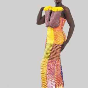 Plus qu’un vêtement, cette robe est une œuvre d’art, un dialogue entre force et couleur, entre tradition et modernité. Conçue pour la femme Kroskel qui avance avec assurance, elle incarne la puissance de celles qui tissent ensemble un avenir lumineux. Le buste, minutieusement travaillé, est inspiré des cases africaines et de leurs toits de paille. Les nœuds délicatement tissés viennent se poser comme des symboles de protection et d’ancrage, tandis que la couleur jaune éclatante illumine l’ensemble, porteuse d’espoir et de renouveau. Sa coupe majestueuse met en valeur la silhouette avec une jupe montante qui épouse la taille et vient se fixer au buste grâce à de sublimes petits boutons, créant une transition harmonieuse entre les textures et les volumes. Son dos nu et sa longue fente dans le dos apportent une touche de sensualité et de liberté, offrant une aisance parfaite à chaque mouvement. Réalisée en plus de 100 heures de travail, cette robe est un hommage au savoir-faire artisanal d’exception. Elle est destinée à celles qui osent, qui inspirent et qui laissent une empreinte indélébile sur leur passage.